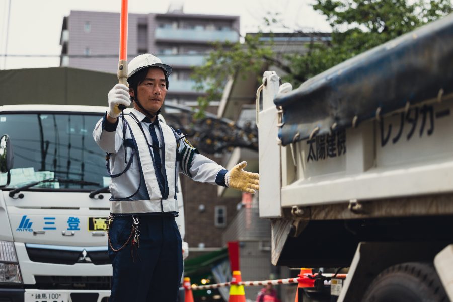 誘導棒でトラックを誘導するスタッフ